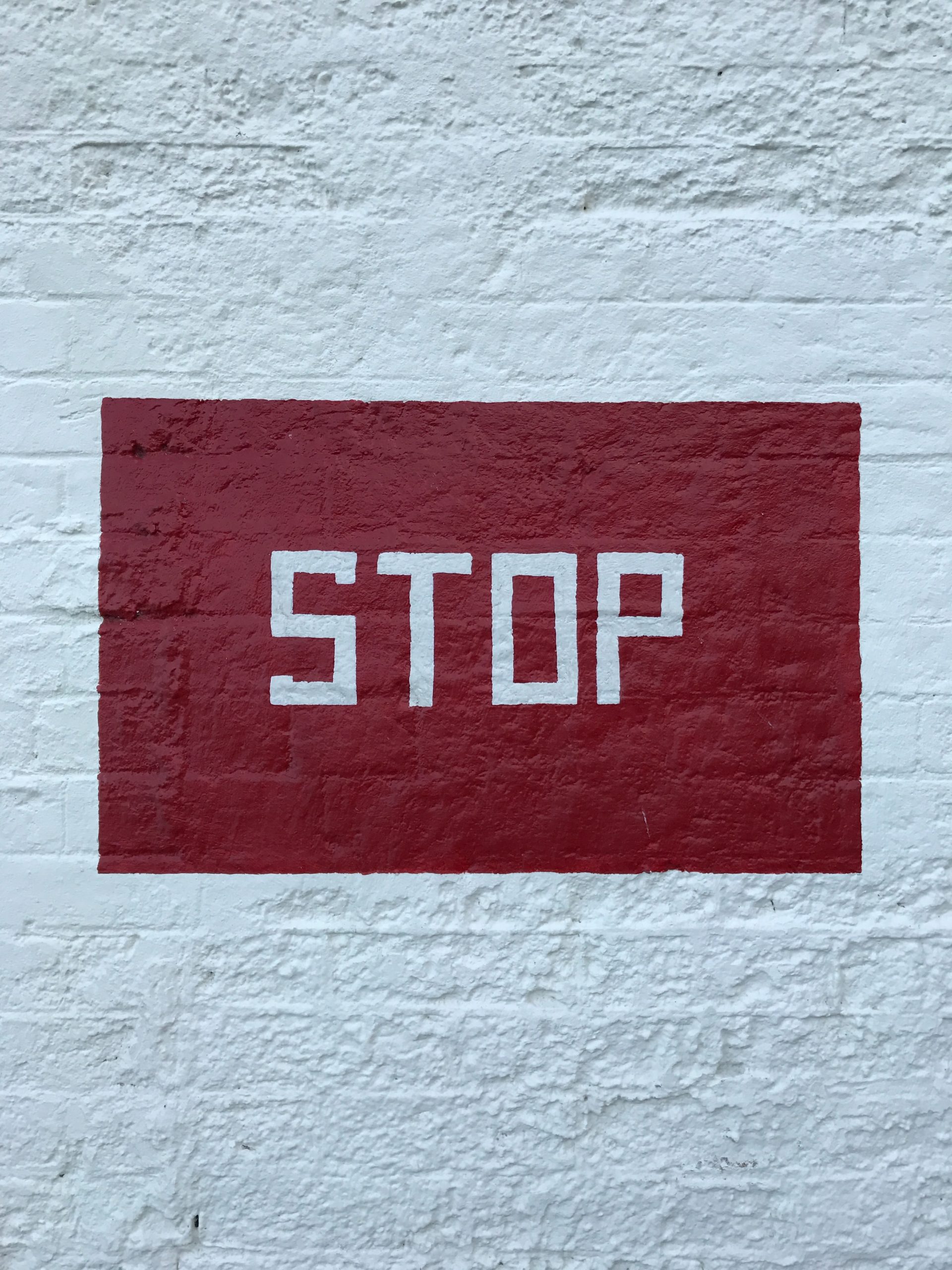 jana-knorr-d-JNCzsRDFE-unsplash stop, segnale di stop, scriita su muro bianco